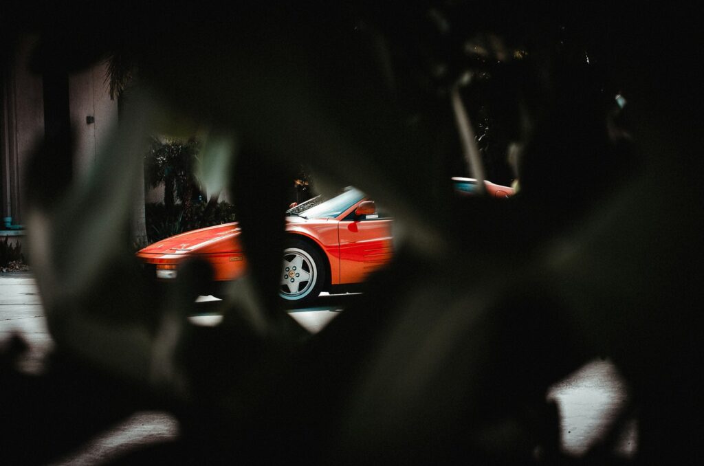 a red sports car driving down a street at night