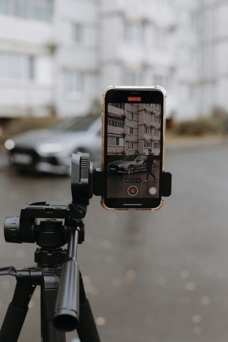 A smartphone on a tripod capturing an urban environment with a person walking by.